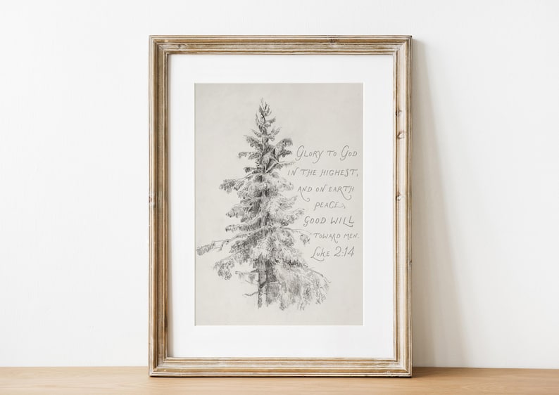 May include: A framed print with a pencil sketch of a fir tree. The artwork includes handwritten text with the words "Glory to God in the highest, and on earth peace, good will toward men, Luke 2:14". The frame is a light brown colour.