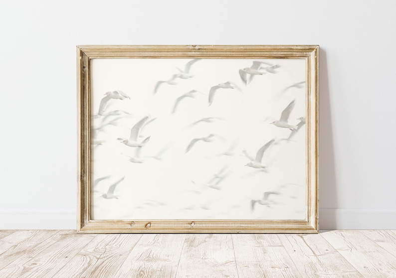 May include: A framed print of a white background with a flock of gray birds in flight. The birds are all facing the same direction and are flying in a loose formation.