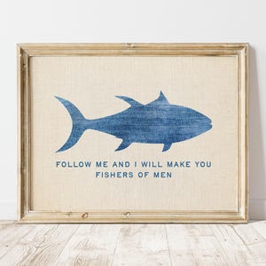 Könnte beinhalten: Gerahmtes Wandbild mit einer blauen Fischsilhouette auf beigem Hintergrund. Unter dem Fisch ist der Text "FOLLOW ME AND I WILL MAKE YOU FISHERS OF MEN" gedruckt. Der Rahmen ist hellbraun. Dekorative Wandkunst.