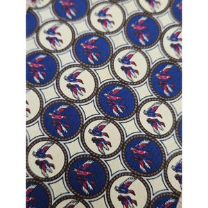 Puede incluir: Primer plano de una tela estampada con un diseño repetido de pájaros. Los pájaros son rojos y blancos, sobre un fondo azul dentro de marcos circulares. Los círculos están dispuestos sobre un fondo color crema.