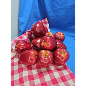 May include: A cluster of shiny, deep red apples with smooth skins and visible stems, arranged in a pile. The apples exhibit rounded shapes and varying shades of crimson, reflecting light on their surfaces, creating a bright and vibrant display.