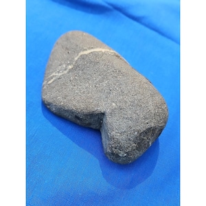 Puede incluir: Una taza de cerámica blanca con asa negra y el texto "But First, Coffee" en negrita negra. La taza se encuentra sobre un fondo borroso, sugiriendo un ambiente acogedor.