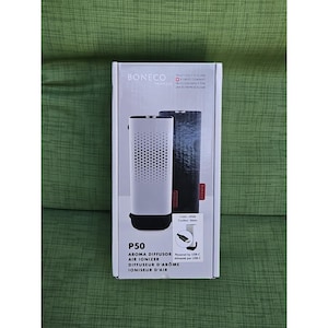 May include: A white and black BONECO P50 aroma diffuser and air ionizer in its original packaging. The box features the product name, a diagram, and the words "AROMA DIFFUSOR", "AIR IONIZER", "DIFFUSEUR D'ARÔME", and "IONISEUR D'AIR".