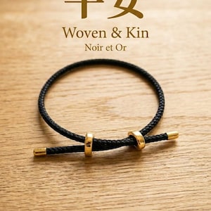May include: A black woven bracelet with gold-coloured details. The bracelet has a circular design with two gold rings and gold-tipped ends. The image includes the text "Woven & Kin Noir et Or" and Japanese characters.