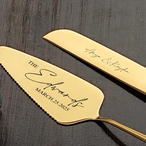 以下が含まれることがあります： 「The Edwards, March 25, 2025」と刻まれた金のウェディングケーキサーバー。2本目の金のナイフも写っており、「Arya & Kayden」と刻まれています。