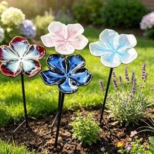Può includere: Quattro picchetti da giardino in ceramica a forma di fiore con finiture lucide nei colori rosso e bianco, rosa chiaro, blu scuro e azzurro. Ogni fiore è montato su una sottile asta di metallo nero da inserire nel terreno del giardino.