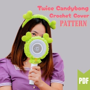 以下が含まれることがあります： Twice Candybongライトスティック用の緑色の編み物カバー。ハート型のアクセントが付いたお揃いのヘッドバンド付き。「Twice Candybong Crochet Cover PATTERN」の文字はピンク色。PDFアイコンが表示されています。