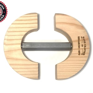 May include: A wooden tool for making hat brims, with a metal rod in the center. It is hand-crafted by Renascent Mfg. and says "Hand Crafted by Renascent Mfg."