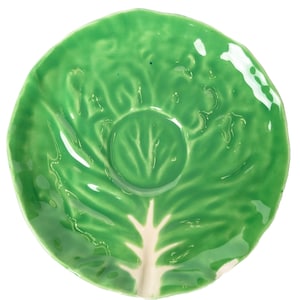 May include: A ceramic plate shaped like a green lettuce leaf. The plate has a glossy finish and a central, raised area resembling the heart of the lettuce. The stem is a creamy white colour.