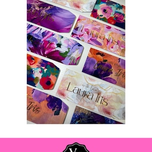 May include: A selection of vibrant gift tags with floral watercolour designs in shades of purple, pink, and gold. Some tags feature the names "Laura Iris" and "Tris" in gold script, along with the phrase "with love."