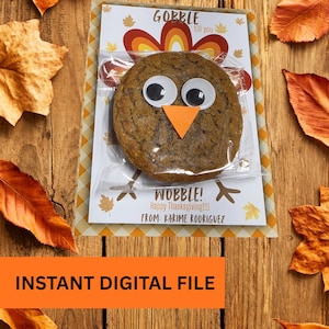 May include: A Thanksgiving-themed cookie in a clear plastic bag, decorated with large googly eyes and an orange beak, resembling a turkey. The packaging includes the text "GOBBLE till you WOBBLE! Happy Thanksgiving!!!!" and "INSTANT DIGITAL FILE".
