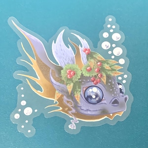 May include: A purple and gold dragon with a wreath of green leaves and red berries. The dragon has large blue eyes and is swimming in a blue background with white bubbles.