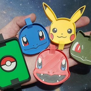 Może przedstawiać: Kolekcja kolorowych, drukowanych w 3D postaci Pokemonów. Zawiera Pikachu, Squirtle, Charmandera, Bulbasaur i zielono-czarny wzór Pokeballa. Każda postać ma pętlę do mocowania.