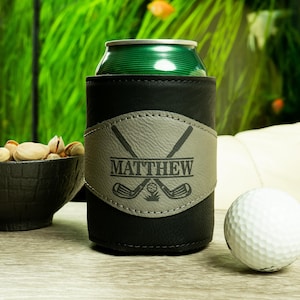 May include: Black leather can cooler with a gray leather patch featuring crossed golf clubs and the name "MATTHEW".
