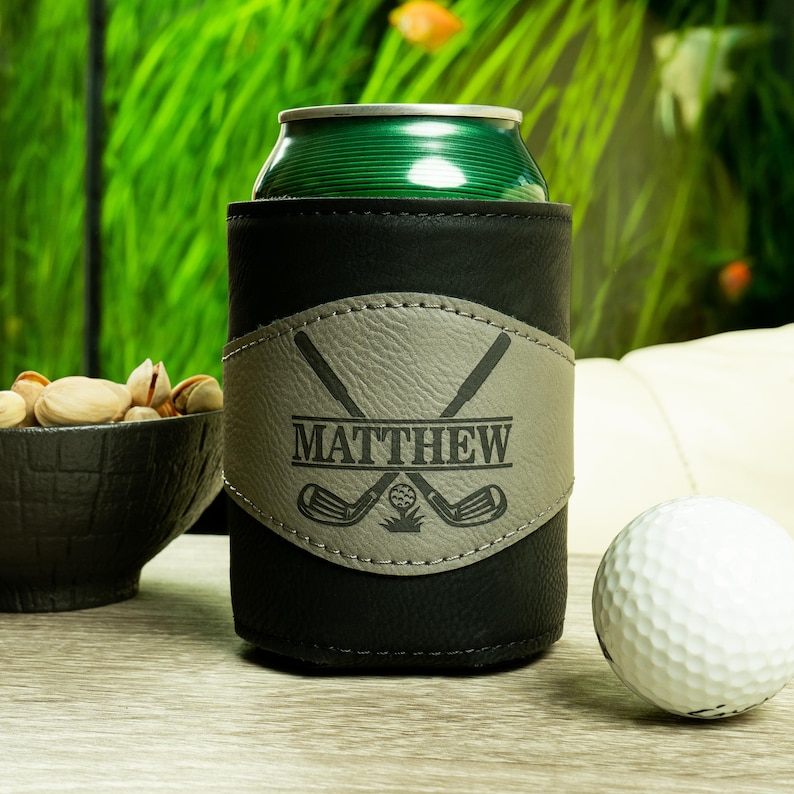 May include: Black leather can cooler with a gray leather patch featuring crossed golf clubs and the name "MATTHEW".