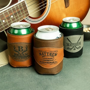 May include: Three personalized leather can coolers with different designs. The first cooler is brown with a deer head and the name "Brian" with the date "10.5.2025" and the text "Groomsman". The second cooler is brown with the name "Matthew" and the date "11.10.2025" and the text "Groomsman". The third cooler is black with a golf club design and the name "Matthew".