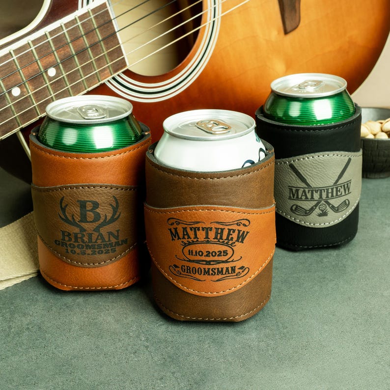 May include: Three personalized leather can coolers with different designs. The first cooler is brown with a deer head and the name "Brian" with the date "10.5.2025" and the text "Groomsman". The second cooler is brown with the name "Matthew" and the date "11.10.2025" and the text "Groomsman". The third cooler is black with a golf club design and the name "Matthew".