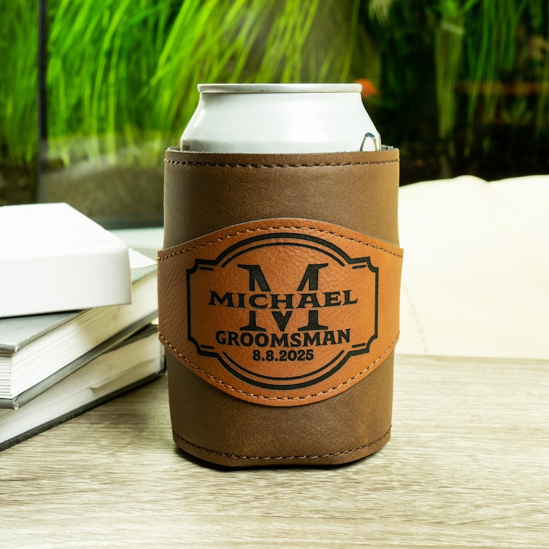 May include: Brown leather can cooler with a personalized patch that says "Michael IV  Groomsman 8.8.2025"