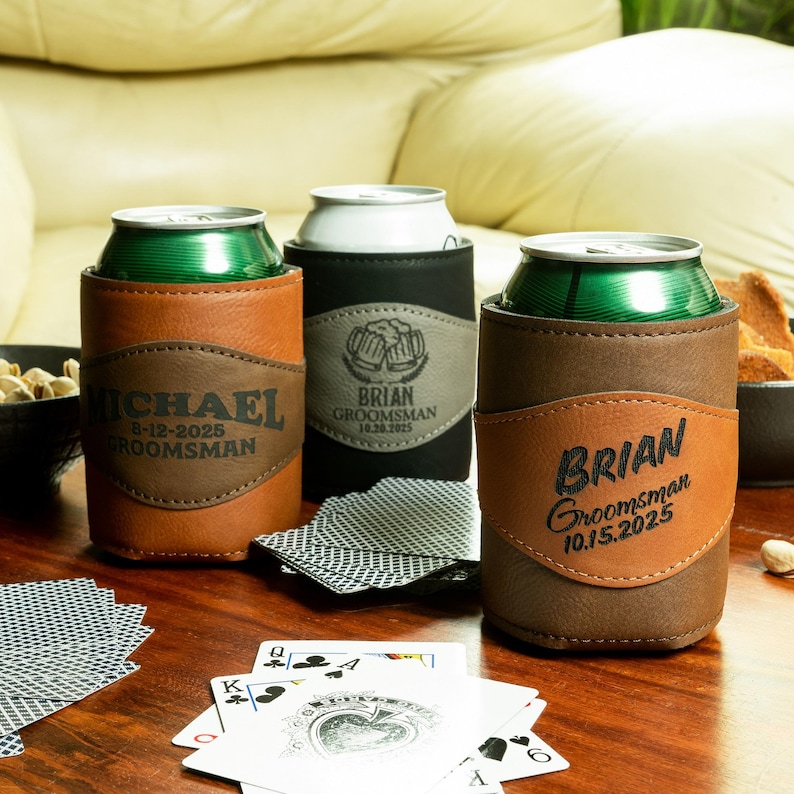 May include: Three personalized brown leather can coolers with black text. The coolers have the names "Michael", "Brian", and "Brian" with the date and the word "Groomsman".