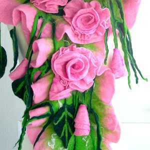 May include: A pink felt flower scarf with green leaves and pink flowers. The scarf is draped over a white mannequin.