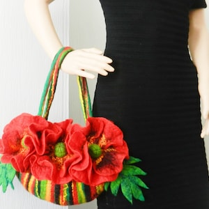 Peut inclure: Un sac à main en feutre rouge avec un motif de fleurs de pavot. Le sac a des rayures vertes et jaunes et des feuilles en feutre vert.