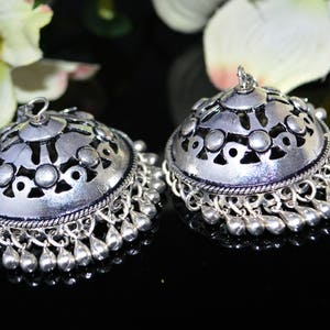 May include: A pair of silver earrings with a decorative, openwork design and dangling beads.
