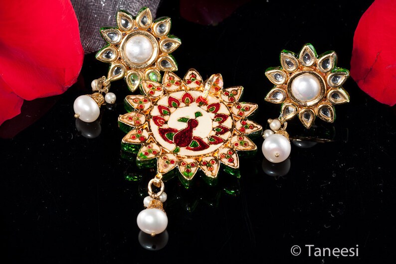 May include: A set of three gold-tone earrings with white pearls and green and red enamel accents. The center earring features a peacock design.