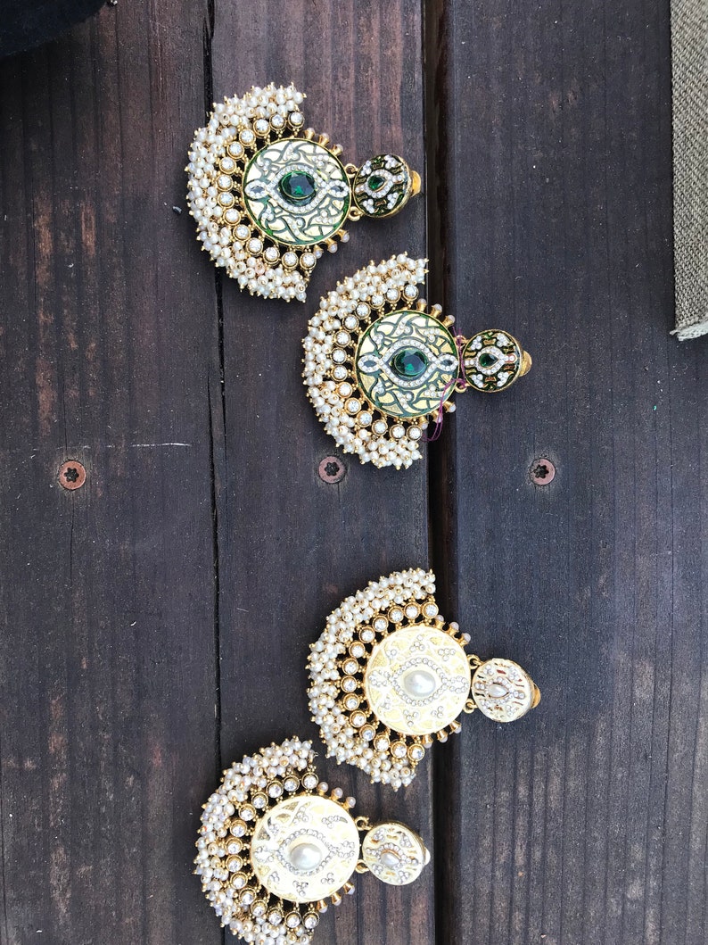 May include: Four pairs of gold earrings with pearl accents. Each earring features a round, decorative center piece with green and white enamel designs.