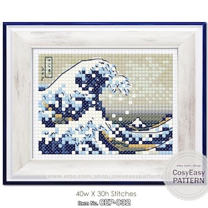 Puede incluir: Un patrón de punto de cruz de la Gran Ola de Kanagawa de Katsushika Hokusai, una famosa estampa japonesa en madera. El patrón está enmarcado en un marco de madera blanco con un borde azul. El patrón tiene 40 puntos de ancho y 30 puntos de alto. El patrón está disponible para descargar e imprimir. El patrón está disponible en Etsy.com/shop/CosyEasyPattern.