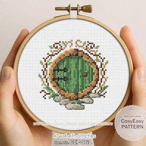 May include: A cross-stitch pattern of a green hobbit door, framed in a wooden embroidery hoop. The door is surrounded by brown vines and sits on a stone base. The pattern is 47w x 47h stitches.