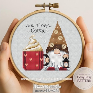 May include: Cross-stitch embroidery in a wooden hoop, featuring a red coffee mug, a gnome with a lantern, and the text "but first, Coffee." The gnome wears a brown hat and has a white beard. The pattern is 55 stitches wide and 57 stitches high.