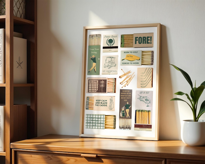 May include: A framed collage of vintage matchbox labels with a golf theme. The labels feature illustrations of golf clubs, golf carts, and golfers. The text on the labels includes "FORE!", "Born to Golf", "Forced to Work", "Keep Calm and Blame the Caddie", and "St Andrews".