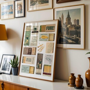 May include: A framed collage of vintage matchboxes with golf-themed illustrations and text, including "FORE!" and "Born to Golf, Forced to Work". The collage is displayed on a white wall with other framed pictures.