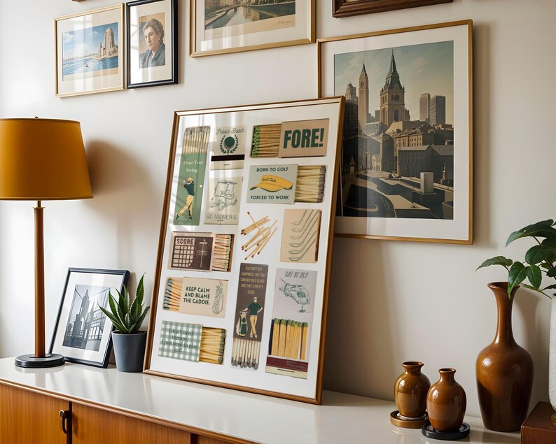 May include: A framed collage of vintage matchboxes with golf-themed illustrations and text, including "FORE!" and "Born to Golf, Forced to Work". The collage is displayed on a white wall with other framed pictures.