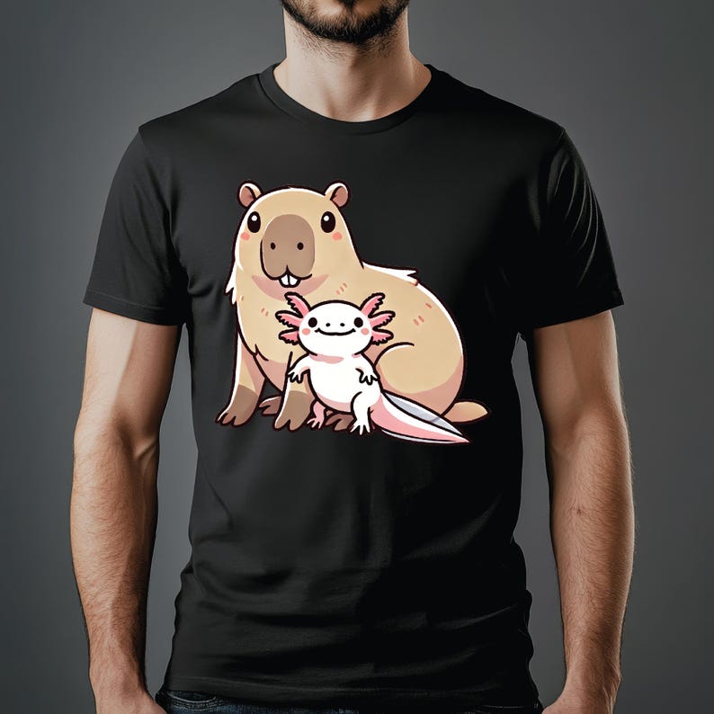 Pode incluir: Uma camiseta preta com uma imagem de desenho animado de uma capivara e uma axolotl. A capivara &eacute; marrom e tem o nariz rosa. A axolotl &eacute; branca com br&acirc;nquias rosas.