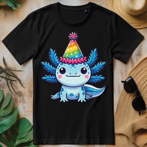 Könnte beinhalten: Schwarzes T-Shirt mit einem Cartoon-Axolotl, das einen Regenbogen-Partyhut trägt. Der Axolotl ist blau mit rosa und weißen Details.