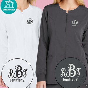 May include: A white and a dark gray zip-up scrub jacket, each featuring a round neckline and long sleeves. Both jackets are embroidered on the left chest with a decorative monogram of the letters RBT above the name Jeniffer S. in a script font.
