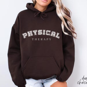 Puede incluir: Una sudadera con capucha marrón oscuro con una impresión blanca que dice "PHYSICAL THERAPY" en una fuente de estilo universitario vintage.