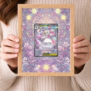 May include: A framed Pokémon trading card with a character in a white dress and pink details. The card is set against a stained-glass style background with a wooden frame. The card reads "Mega Gardevoir EX" and "Overflowing Wishes".
