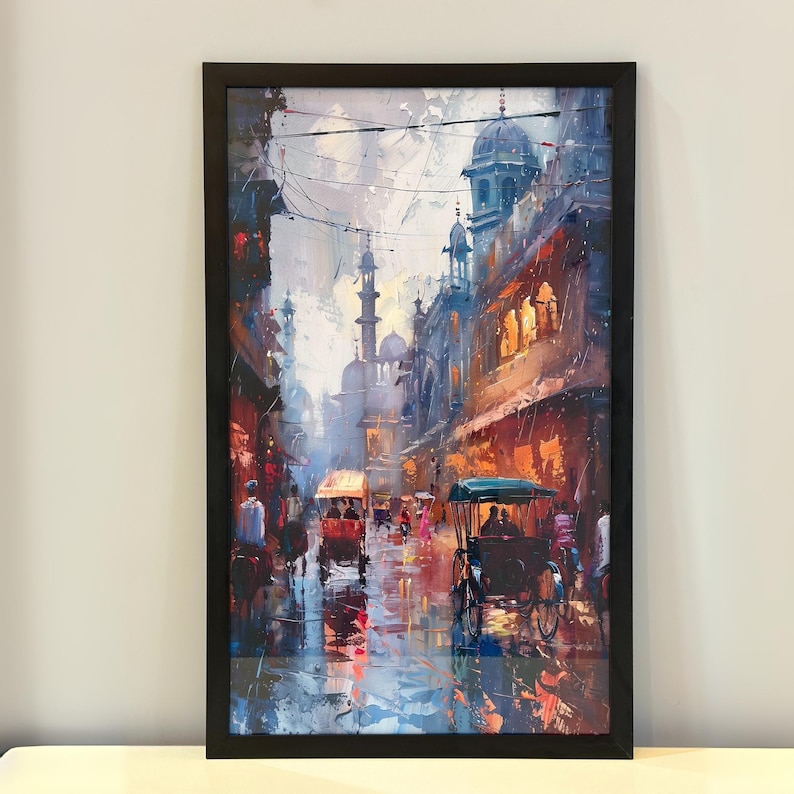 May include: Framed art print depicting a vibrant street scene with buildings, rickshaws, and figures. The artwork features a color palette of blues, oranges, and reds, with a focus on light and shadow. The painting is framed in a black frame.