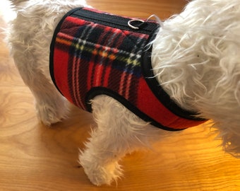 May include: Red and black plaid dog harness with a black adjustable strap and a silver metal D-ring.