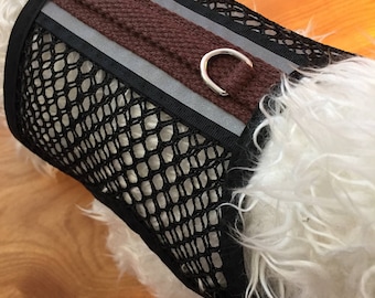 May include: A black mesh dog harness with a brown and silver strap and a metal ring. The harness is designed for small dogs.