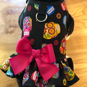 May include: Black dog harness with a pink bow and a colourful sugar skull pattern.
