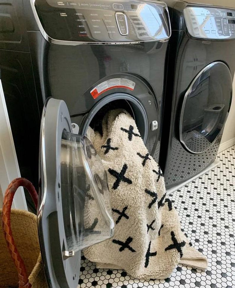 A machine washable rug, hanging out of washing machine, made out of neutraland natural raw materials, in ivory and black by rich class decor