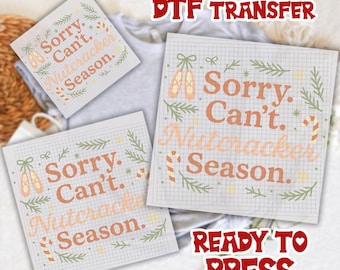 May include: Three DTF transfer sheets with the text "Sorry. Can't. Nutcracker Season." in orange, surrounded by green sprigs, ballet shoes, and candy canes. The words "DTF TRANSFER" and "READY TO PRESS" are also visible in the image.