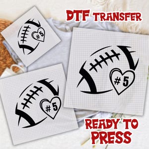 May include: Black football graphic with a heart-shaped design and the number 5. The words "DTF TRANSFER" and "READY TO PRESS" are in red. The design is on a grid paper.