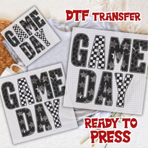 May include: DTF transfer sheets with the words "GAME DAY" in a distressed font. The letters are black and gray with checkered and star patterns. The phrase "READY TO PRESS" is also visible in red.