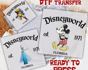 May include: DTF transfer sheets featuring Disney characters. Designs include Wolverine, Mickey Mouse, and Elsa, with "Disneyworld" text, the year "1971", and "Florida" text. The phrase "Ready to Press" is also visible.