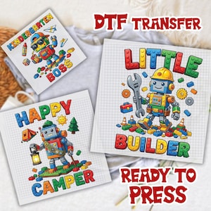 May include: Three square DTF transfer sheets featuring cartoon robots constructed from colorful building blocks. Designs include a robot with the text Kindergarten Boss, a robot with the text Happy Camper, and a robot with the text Little Builder.