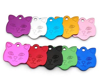 May include: Ten colorful cat-shaped metal pet ID tags. The tags are in various colors including purple, silver, blue, yellow, pink, red, black, green, and blue. Each tag has a cat face design with eyes, a nose, and whiskers.
